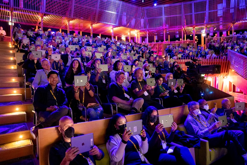  Audience all holding up iPads which they watch a live performance with augmented reality through at TED2022 conference. . 