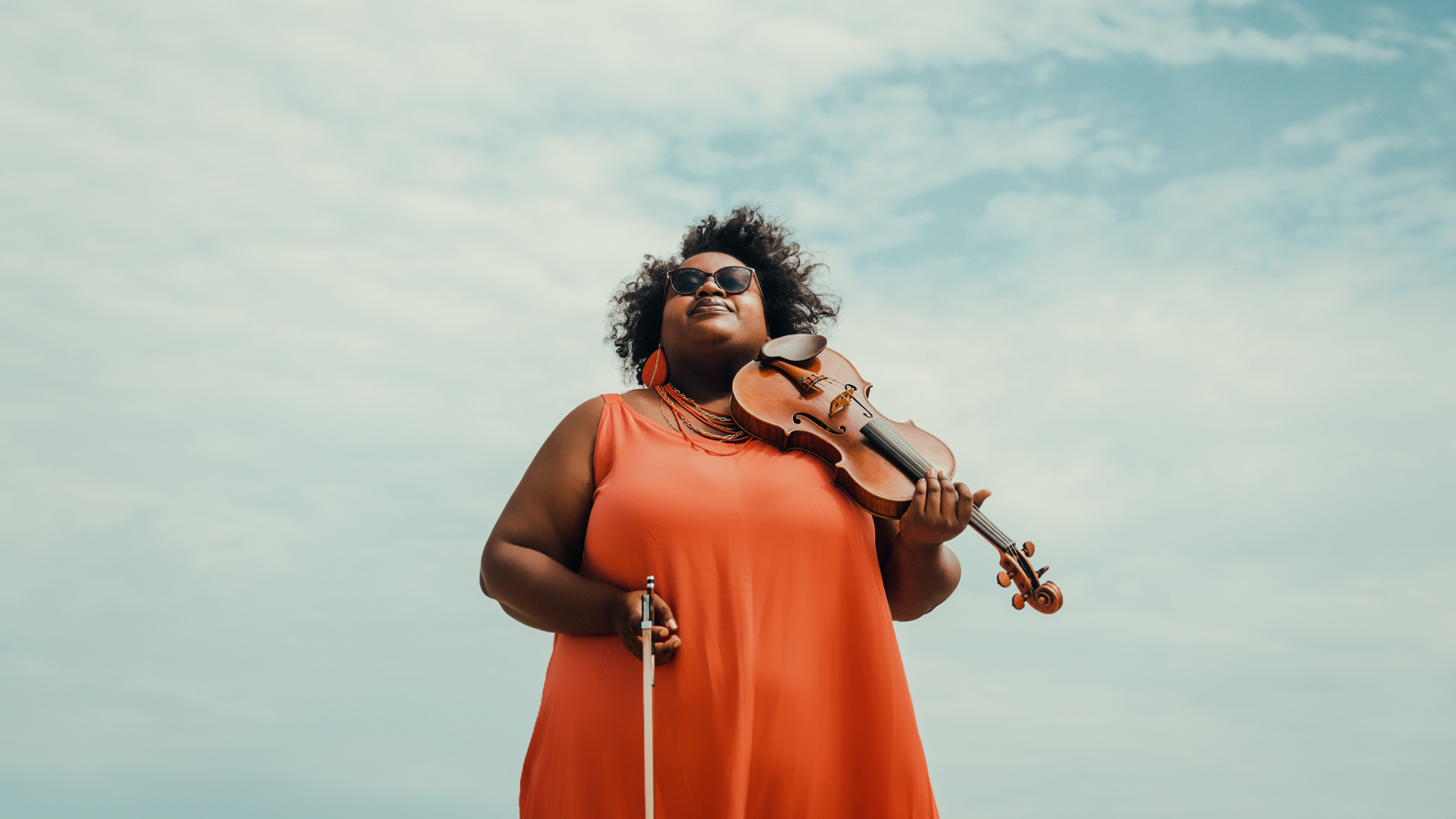 Caitlin Edwards holding a violin looking up into the sky