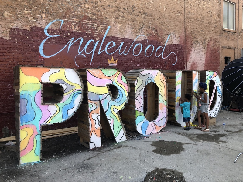  An art installation that reads "Englewood Proud" in color text against a brick wall. 