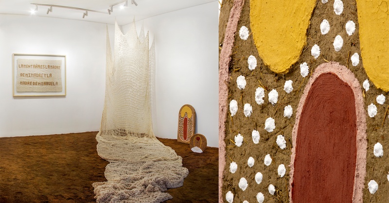  Installation of a white net hanging from the ceiling. Next to it is a small abstract sculpture. 