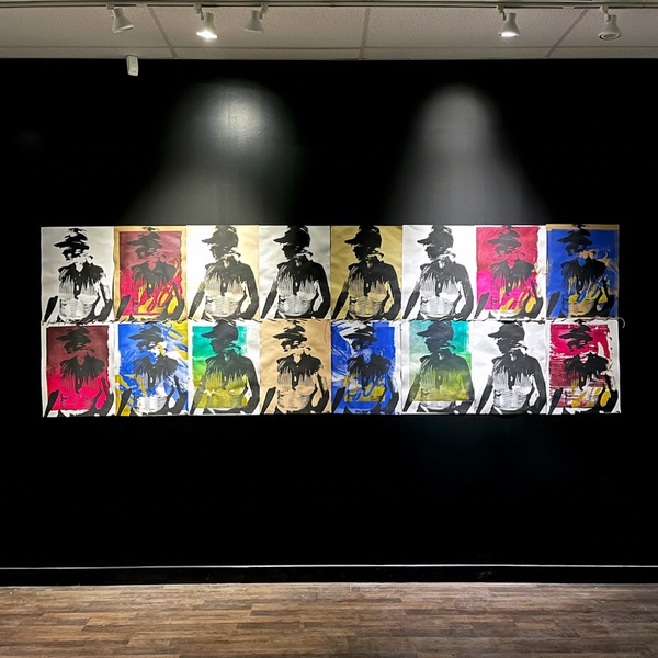  Eight printed images of a person in black ink on top of colorful paper hung on a black wall. 