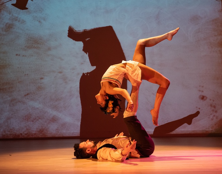  One performer lifts another in the air with their feet. 