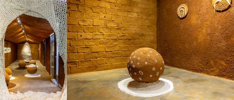  A round yellow ball sits in the middle of a gallery with yellow bricks. 