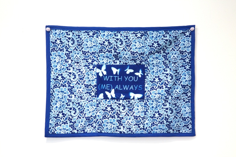  A cyanotype quilt with floral imagery surrounding butterflies in the center that reads "with you (me) always" 