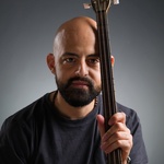 Wanees Zarour, male, brown eyes, full black beard, shaved head, visible buzuq fingerboard near face