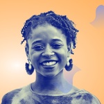 Black African American woman with curly brown hair and earrings smiles face forward to the camera against a soft orange background