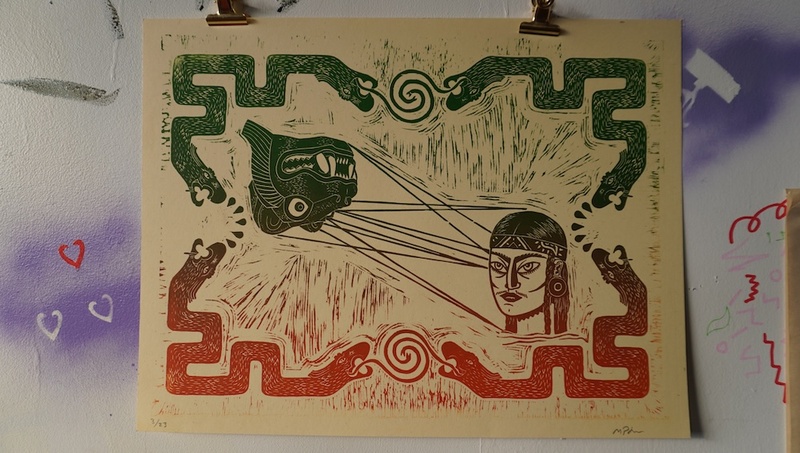  A block print on yellow paper. On one side there is the head of an ancient lion statue holding gaze with a Native individual. They are surrounded by snake like creatures which frame the print in green and red. 