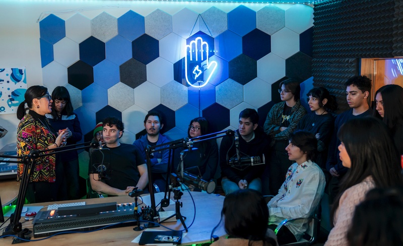  a teacher and a group of students at Lumpen Radio, learning about the studio equipment 