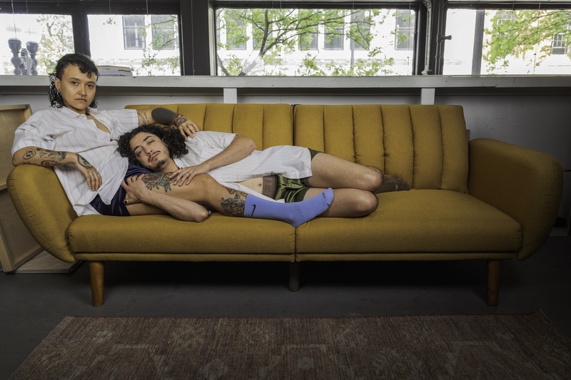  Two people pose for a portrait on an orange couch. 