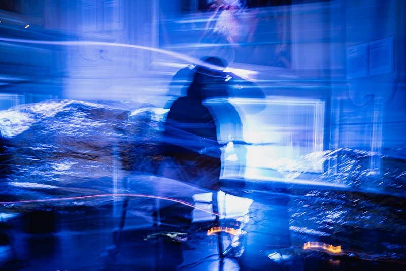  Asian/Femme, Long black hair plays music in a distorted image. The lighting leaves streaks on the picture which is blue and white. 