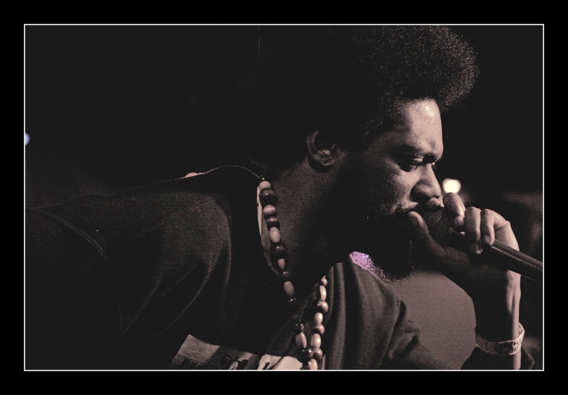  Black and white photo of a black rapper with an afro performing 