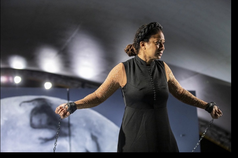  Actor in all black, chains around wrists. Pained expression. 