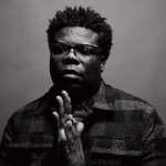 black and white photo of avery r young a dark skinned man in plaid jacket and shirt