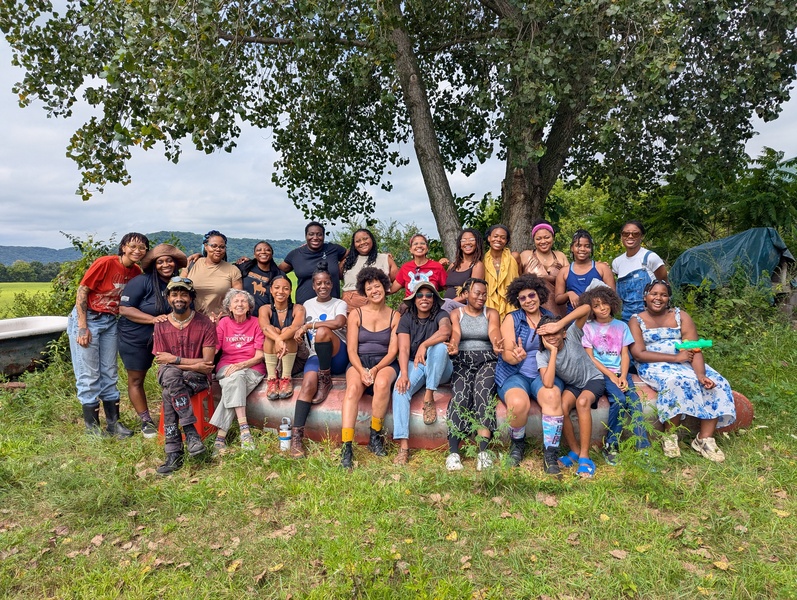  A large group of people smile and pose outside. 