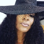 Black woman with long curly brown hair and brown eyes