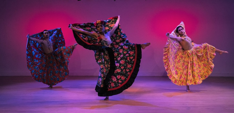  Three performers wearing floral dresses pose in sync. 