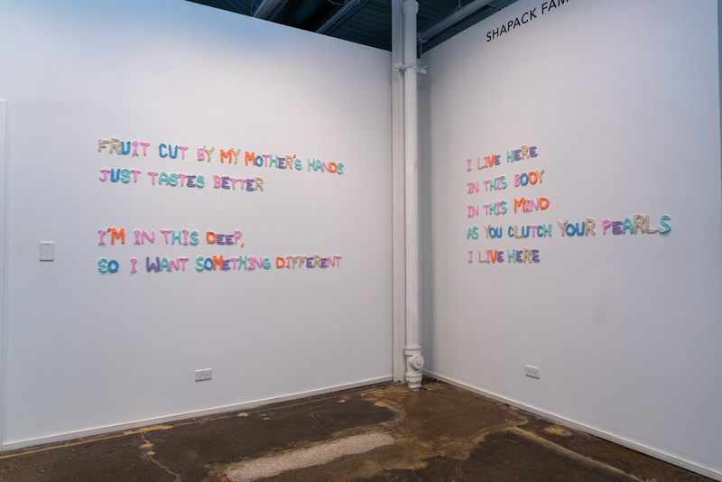  multi-colored crochet text on two gallery walls 