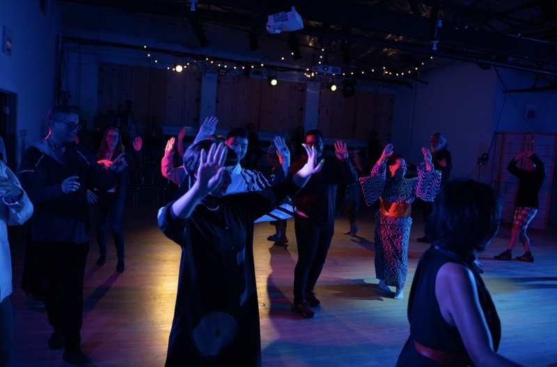  A group of people dancing in a circle, under a blue and red light. 