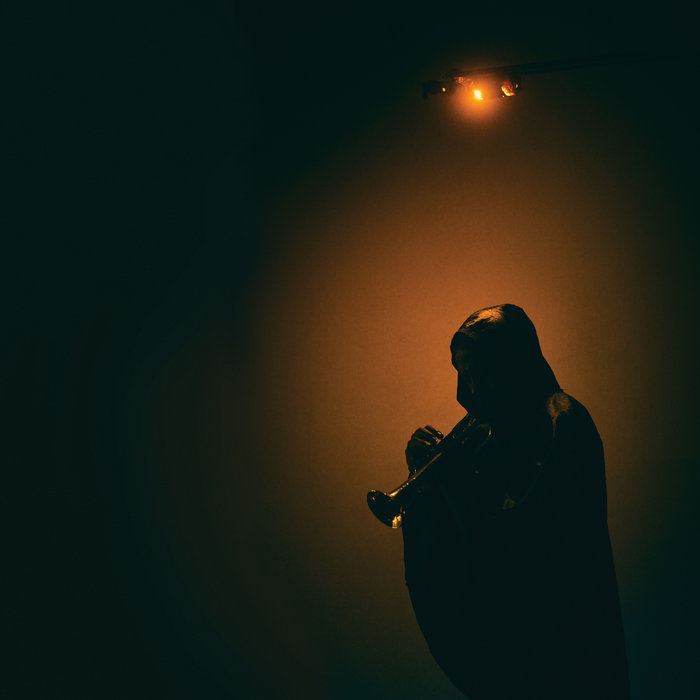 Image of Ben LaMar gay's cover album. The image shows a silhouette highlighted in orange by a street lamp.