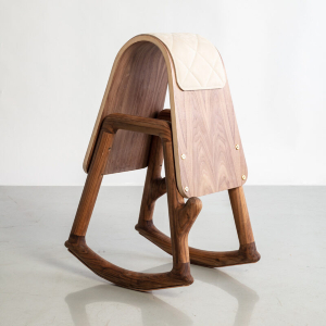 Image of Norman Teague's Sinmi Stool. The stool is made of different colored woods. Two wooden frames support the chair's structure, while another wraps and curves around the frames, providing a place to sit.