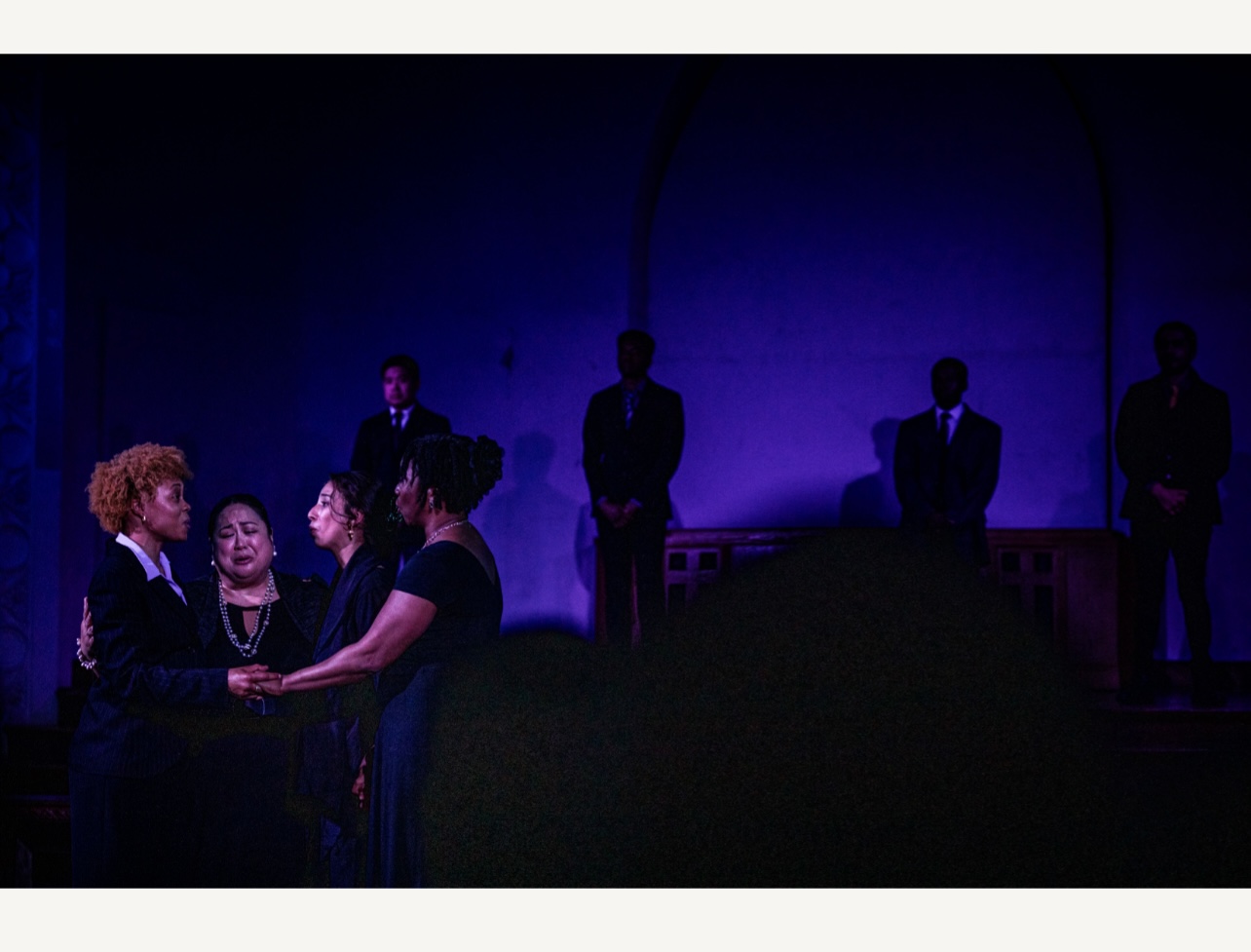  four women in black are in the foreground crying; in back of them are the shadows of their sons killed by gunfire 